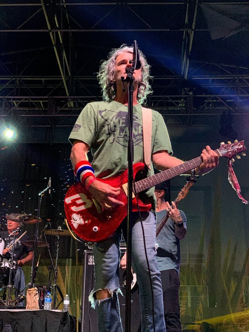 Spank The Monkey guitarist performing under green stage lights