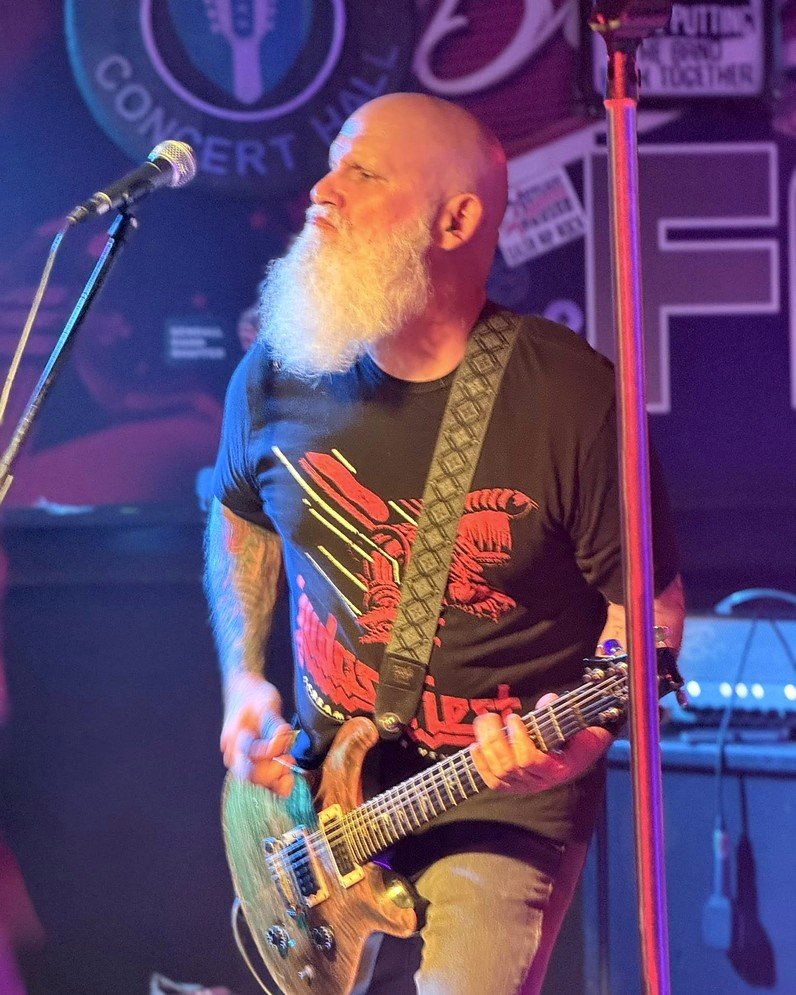 Spank The Monkey guitarist performing live under colorful stage lights